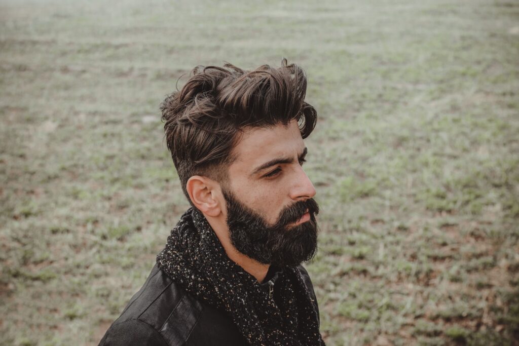man in black leather jacket standing near body of water during daytime
